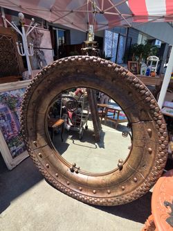 The round mirror features a thick, rustic-style frame.