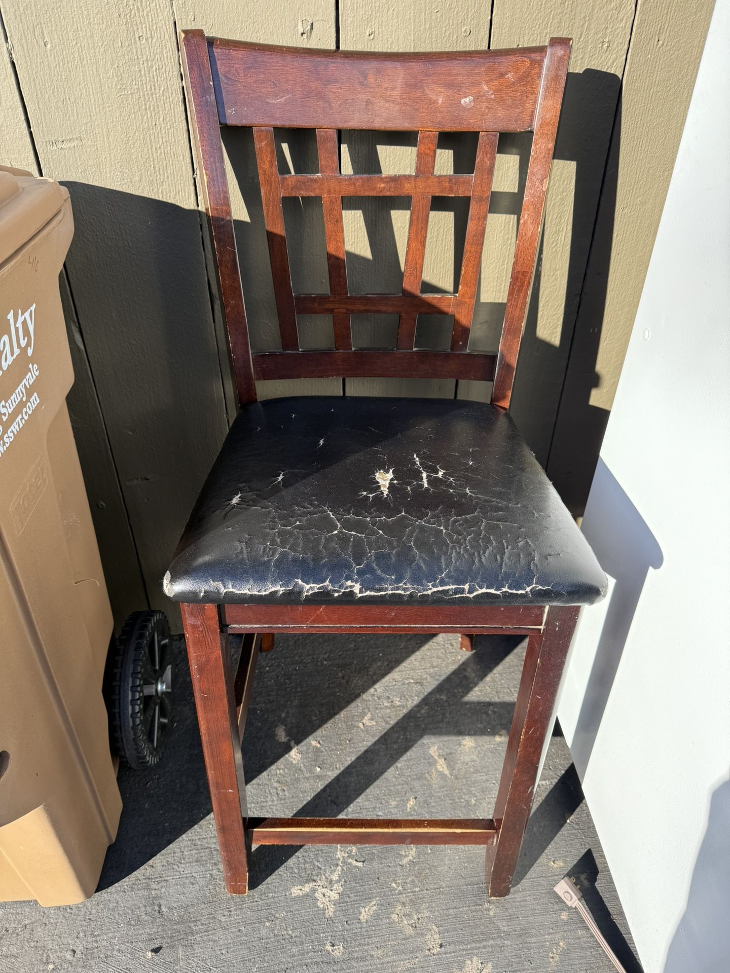 Wooden chair with a black vinyl cushioned seat.