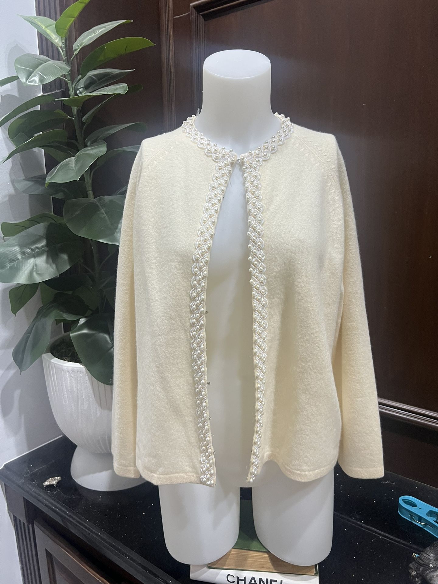 This elegant cream sweater features exquisite pearl detailing along the neckline. Perfect for adding a touch of sophistication to any outfit. Vintage