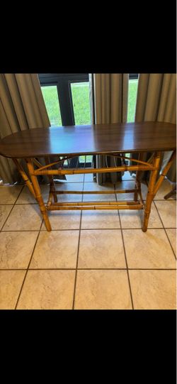 vintage mid-century coastal console or dining table featuring a distinctive bamboo and rattan base with an open lower storage rack