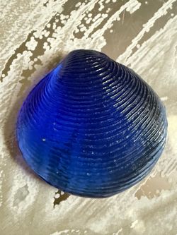 Cobalt Blue Glass Clam Shell Paperweight   Vibrant cobalt blue glass decorative piece is shaped like a clam shell with a textured, ribbed surface. Thi