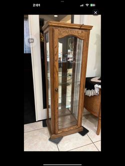 A wooden oak curio cabinet with glass doors and shelves.