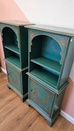 2 dark green, two-tier wooden cabinets featuring painted Chinoiserie-style gold landscape and floral accents