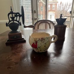 Two vintage coffee grinders and a colorful ceramic mug