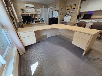 L-shaped light wood office desk with drawers
