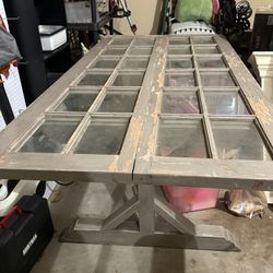 rustic trestle-base dining table made from reclaimed wood and old windows