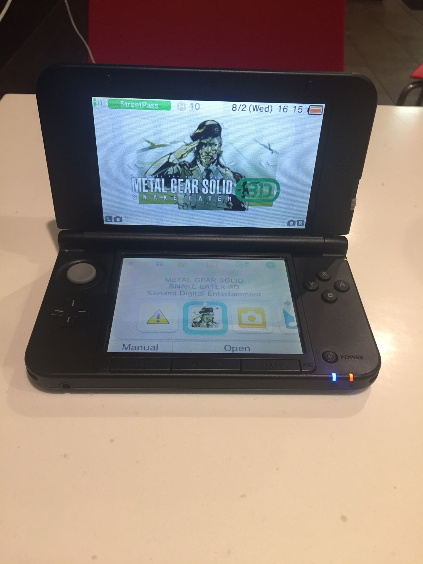 Nintendo 3ds xl with a charger and metal gear solid