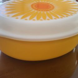 Vintage Pyrex casserole dish. Bright yellow bowl with a white lid. Lid has that classic sunflower daisy pattern in yellow and orange. Bottom says 1 qu