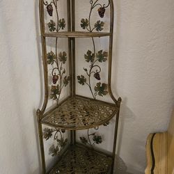 Metal corner shelf unit with four shelves and a vine and leaf design. In excellent, unused condition