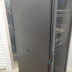 42u APC Rack Enclosure with patch panels and wheels.