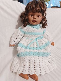A vintage collectible porcelain/vinyl doll with brown hair styled in ringlet curls and dark brown eyes.