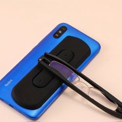 Black folding reading glasses and a case attachable to rear of cell phone