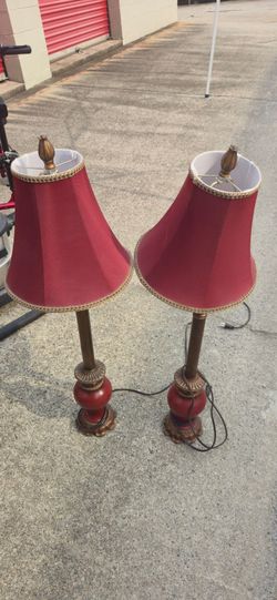 lamps resemble a vintage candlestick design with burgundy fabric shades. They appear to be made of