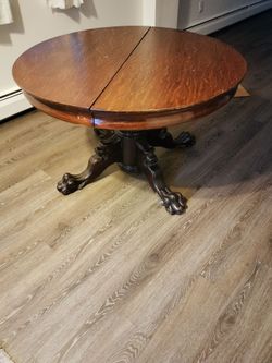 This item is an antique split-pedestal extension dining table with carved claw feet