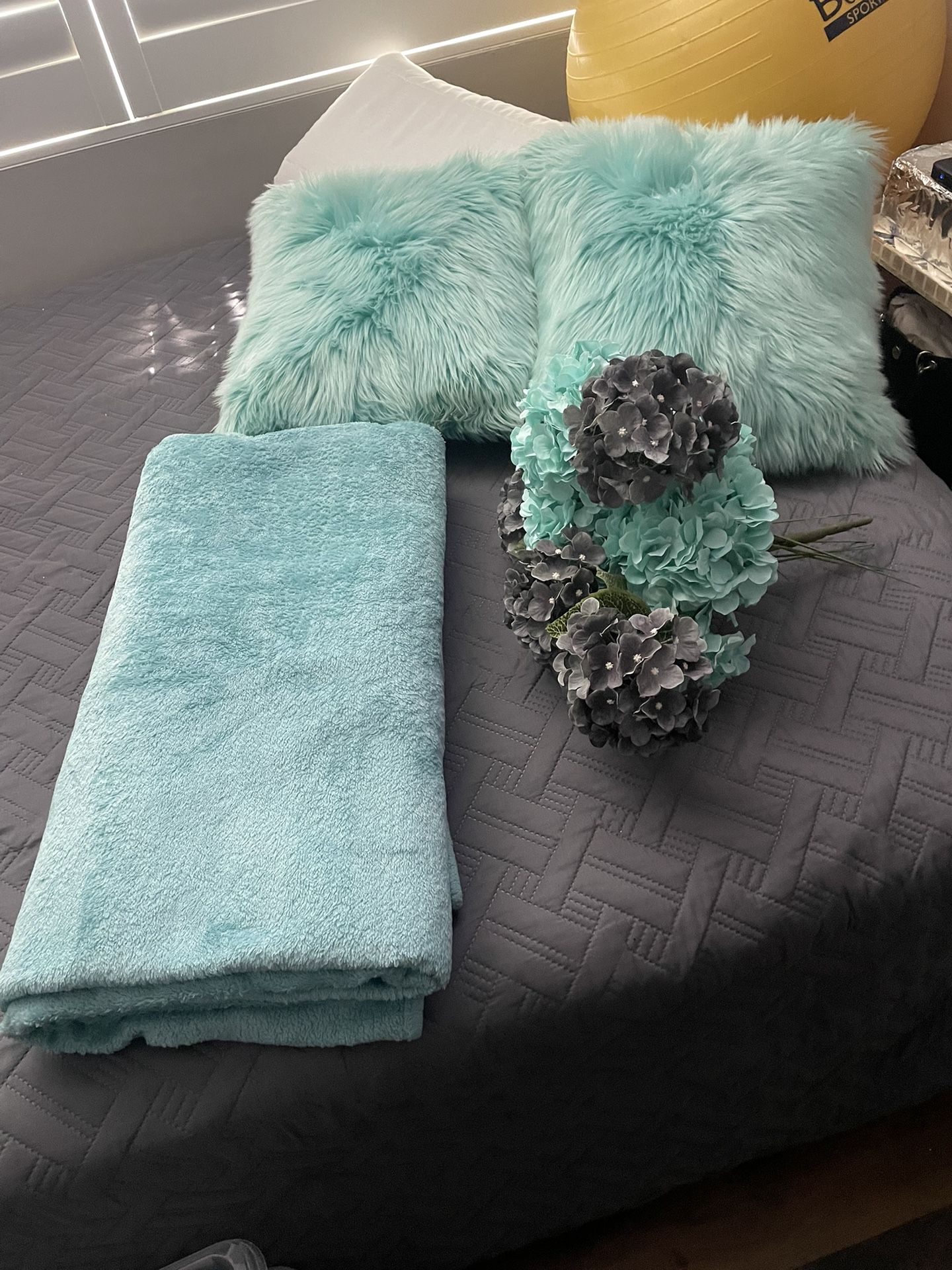 Two turquoise pillows, a turquoise blanket and the gray and turquoise flowers