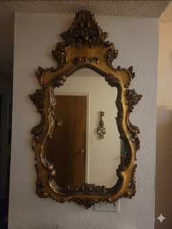 Large gold vintage Rococo-style wall mirror featuring a detailed gold-gilt frame with elaborate scrollwork and acanthus leaf flourishes
