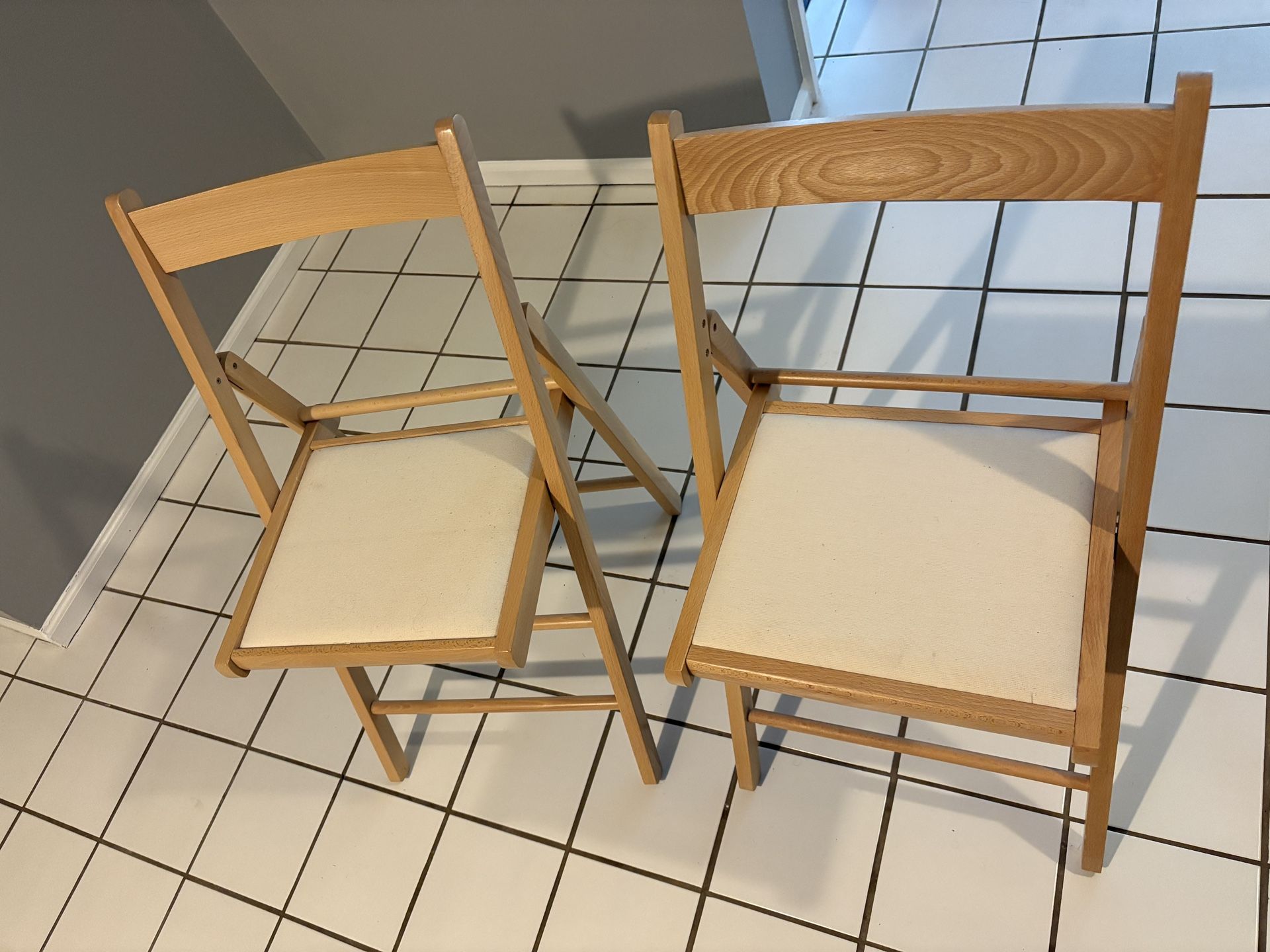 Two Wood and cream fabric folding chairs