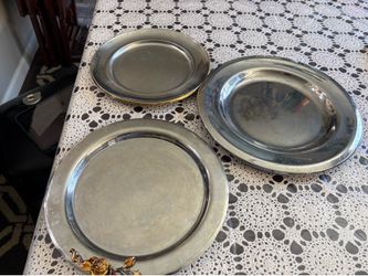 Metallic stainless steel plates set with decorative details. Three metallic silver color plates. One plate has a gold rim. Another plate has a rose an