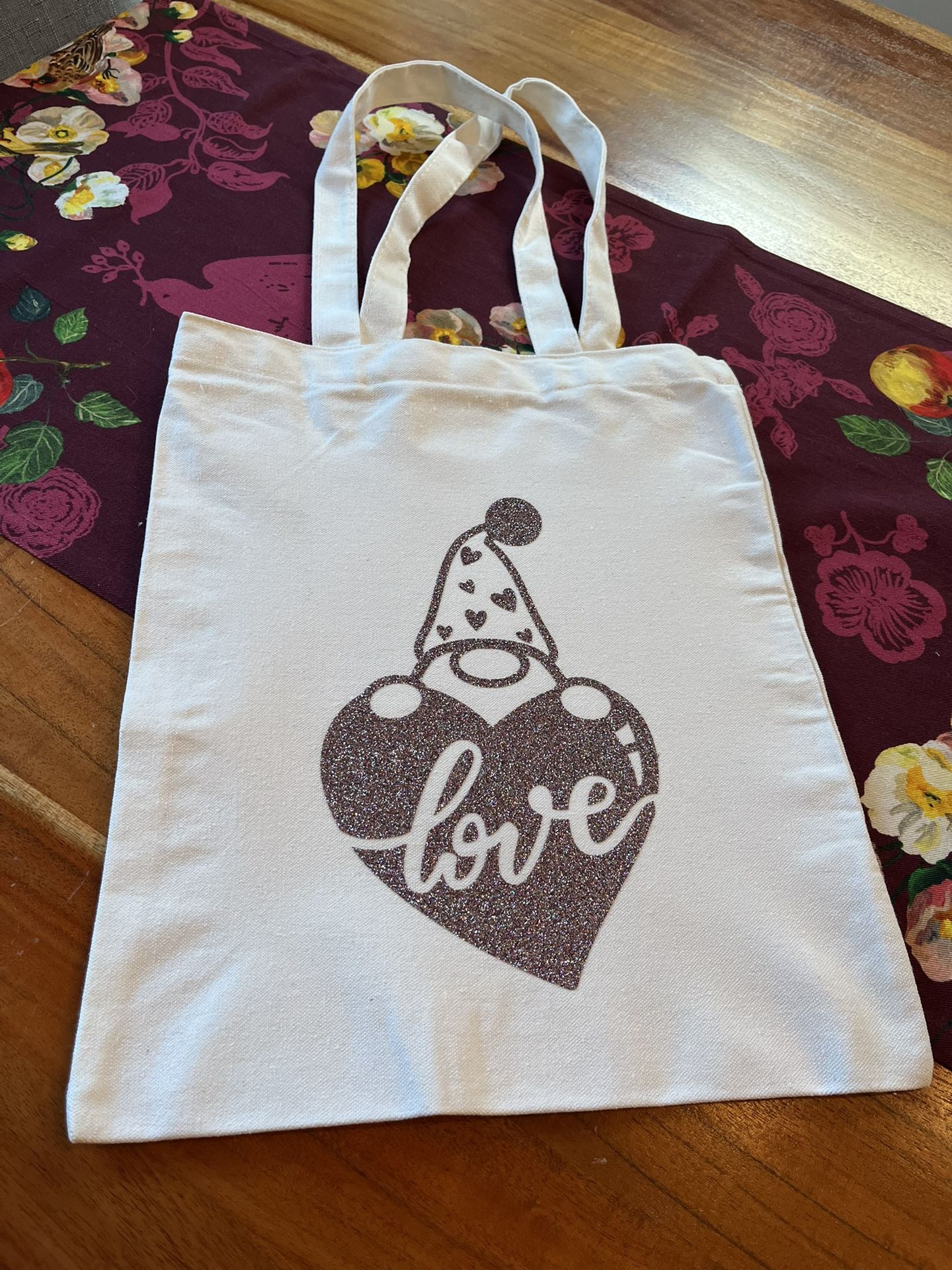 Stylish white tote bag. Features a glittery heart with 'love' text and a gnome. Perfect for casual outings. New. Hand made by me.