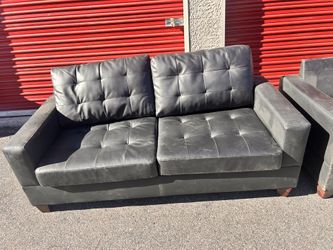 This is a set of black faux leather sofas with tufted cushions