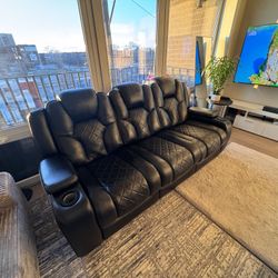 This is a black leather dual power reclining sofa with power-adjustable headrests, USB ports, and storage in the middle and armrest