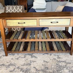 Design by Ashley Mestler rustic brown sofa table with multicolored shelves.