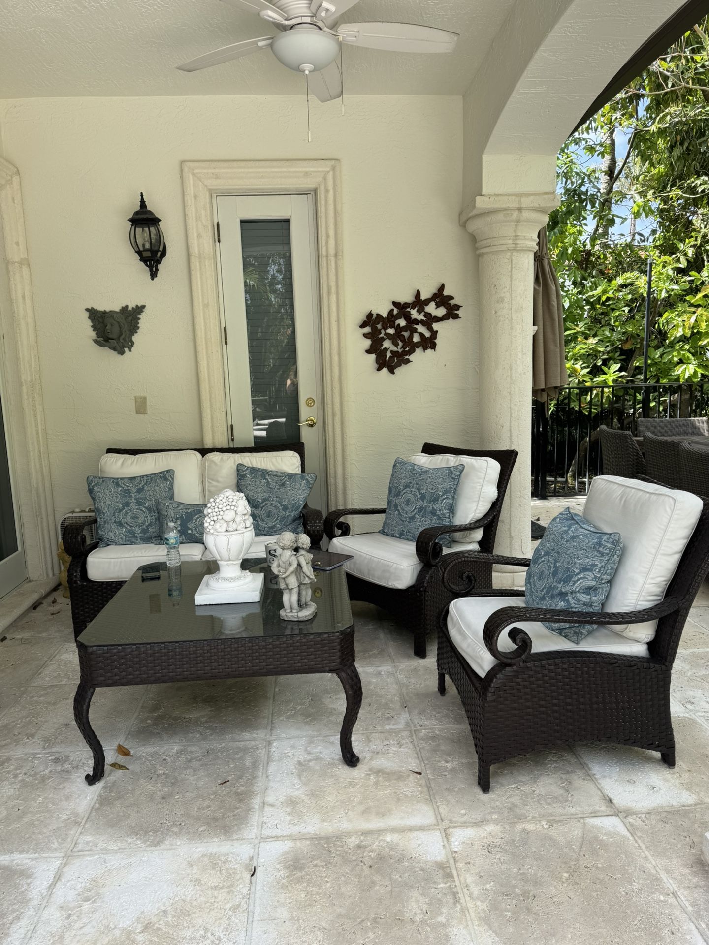 Beautiful outdoor patio set including loveseat, armchair, and glass-top table
