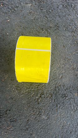 roll of fluorescent yellow thermal transfer labels used for industrial, warehouse, shipping, inventory, or barcode printing.