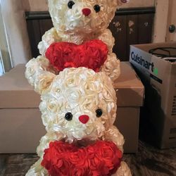 Two Identical Rose Teddy Bears With Floral Arrangements Holding A Heart