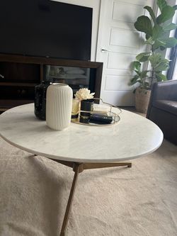 This round coffee table features a beautiful natural white marble top  and a vintage gold metal base,