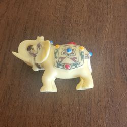 Vintage Miniature Faux Ivory Elephant Figurine Jeweled Caparison Trunk Up 3"long, Height 2.5". Weight 4.25oz plus shipping materials.
Molded from a h