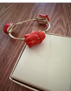 Gold tone wire bangle with three red Buddha head charms