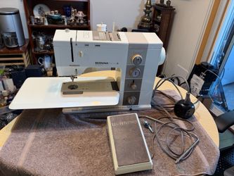 Vintage Bernina Record 930 Electronic sewing machine is made in Switzerland. This white and grey metal machine has a foot pedal, power cord, and a det