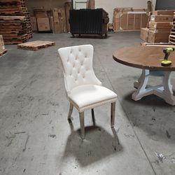 Elegant tufted dining chair in a soft cream fabric with nailhead trim detail. 