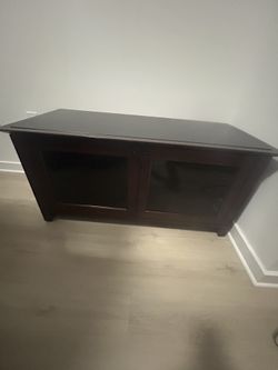 Mohagany Wood Color TV Stand With Smoke Glass Top And Doors . Two Door Nob Vent Back For Storage Space For Storage , Vent Back For Air And Cords .