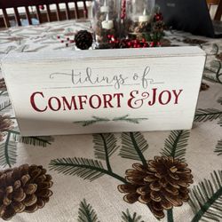 rustic wooden sign featuring the text "tidings of COMFORT & JOY