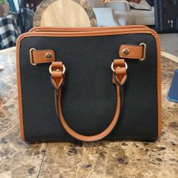 
This Dasein handbag is a stylish black satchel and large tote with a zipper closure and brown faux leather top handles. It features inner pockets, go