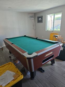 Gently used pool table with cue balls and pool cues for sale.