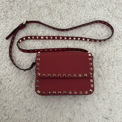 Red leather Valentino Garavani Rockstud shoulder bag adorned with iconic gold pyramid studs.