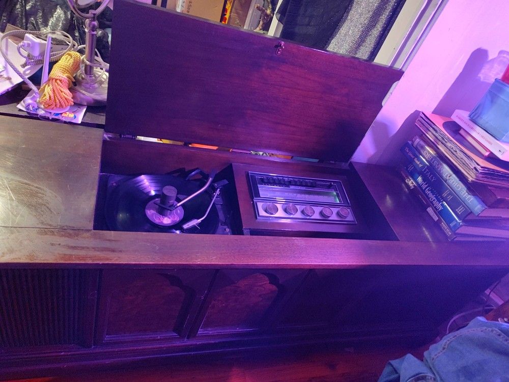 Sylvania stereo console record player with AM/FM radio and 8-track player. Everything is FULLY FUNCTIONAL AND IN EXCELLENT CONDITION.