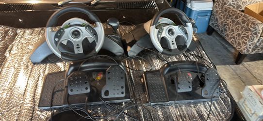 2 x Mad Catz MC2 racing wheels and pedal sets, which are gaming peripherals designed for racing games.