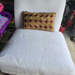 Comfortable white accent chair with decorative pillow.