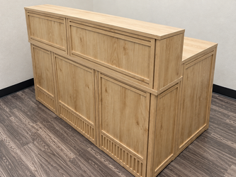 Modern reception/front desk with raised counter in a natural wood finish.