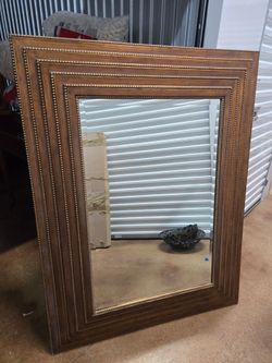 A mirror in a solid wood frame featuring a multi-layered, stepped profile and decorative, fine-grained embossing (in the style of classic or vintage f