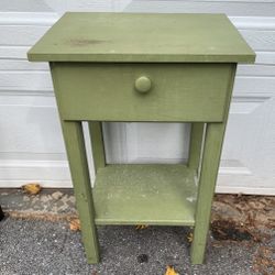 Vintage painted wood side table with one drawer and lower shelf. Measures 17”W x 13”D x 27.5”H. Solid and sturdy with visible paint wear, scuffs, and 