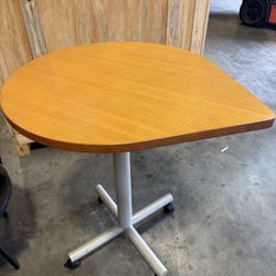 HERMAN MILLER Unique teardrop-shaped wooden top and a silver-colored metal X-base with casters for mobility - 35” x 30” x 38” H - Retail: $1299