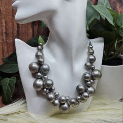 Silver Chunky Graduated Bead Necklace Statement Bold Haute Couture Assorted silver tone beads arranged in graduated manner.
Strung on ribbon with a lo