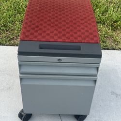 MOBILE PEDESTAL WITH RED CUSHION . Used in good condition the cushion is distressed in a few areas. No key. Can be rekeyed or add a lock on the side. 