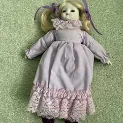 Vintage porcelain collectible doll featuring a bisque, porcelain head and limbs with a fabric body