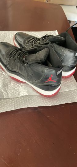Size 11 black and red Nike Air Jordan 11 Retro 'Bred' sneakers featuring signature black patent leather mudguards and translucent red outsoles